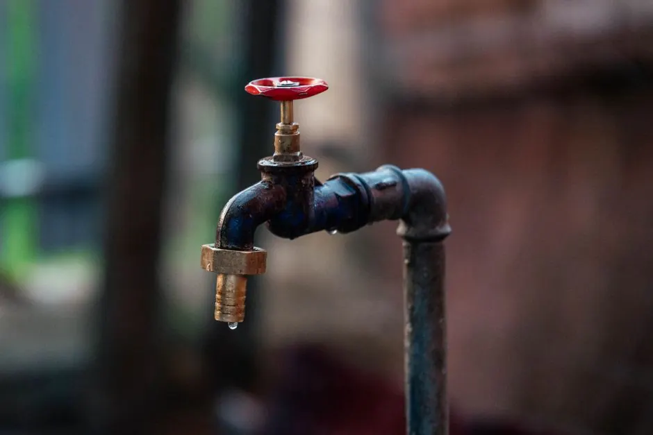 Red-handled shutoff valve on an outdoor water pipe